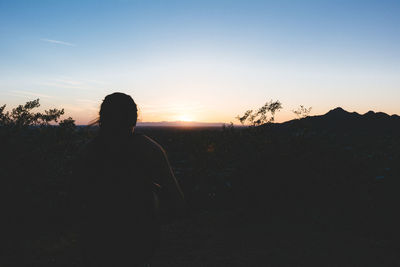 Silhouette of man standing on landscape against clear sky