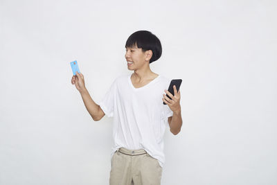 Young woman using mobile phone against white background