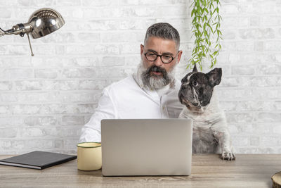 Freelance man working from home with his dog sitting together in office person