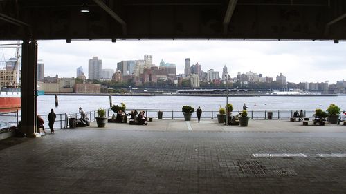 People by river against buildings in city