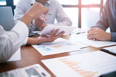 Midsection of business people discussing documents in office