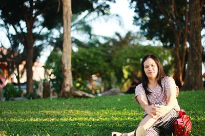 Portrait of smiling young woman sitting in park