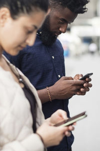 Young friends using mobile phones in city