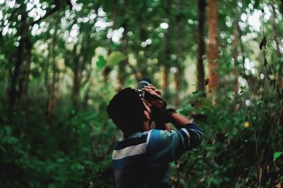 Rear view of a man on tree in forest