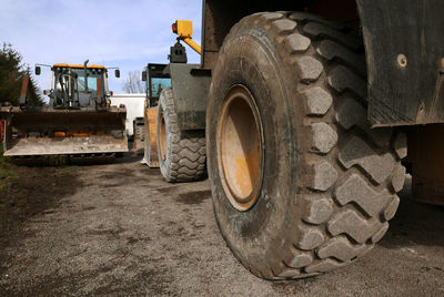 Earth movers on field against sky