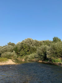 Scenic view of river against clear blue sky