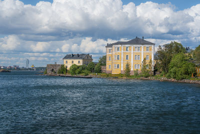 Buildings by river against sky