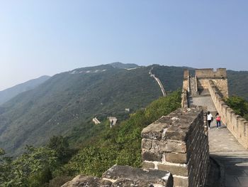 Tourists leading towards great wall of china against clear sky