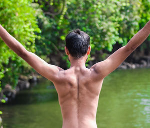 Rear view of shirtless man in forest