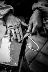 Midsection of man sharpening scissor