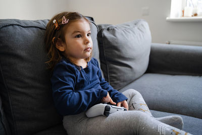 Smiling girl sitting on sofa at home