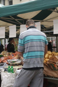 Rear view of man standing at market stall in city