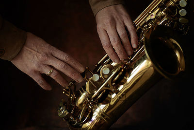 The hands of a musician on the saxophon - an ancient musical wooden instrument popular in jazz music