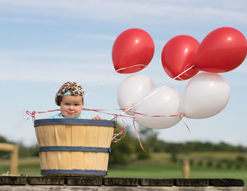 Portrait of boy with balloons against sky