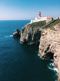 Lighthouse by sea against sky