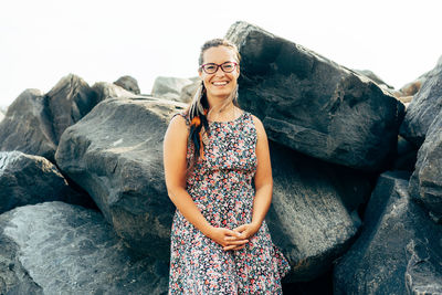 Portrait of smiling woman standing against rocks-