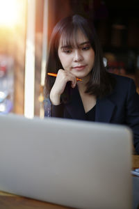 Portrait of young woman using phone while sitting on table