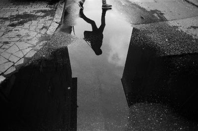 Low section of person on puddle in city