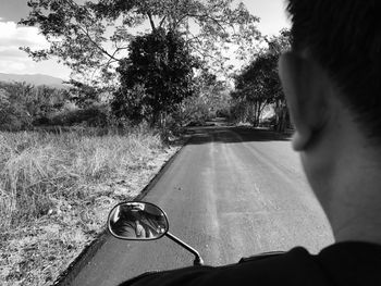 Close-up of hand on road against trees