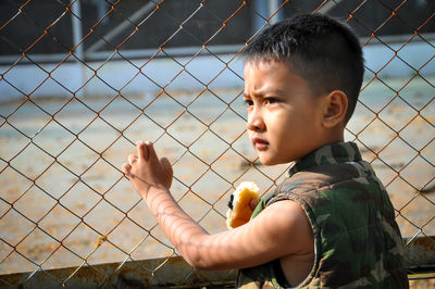 Boy looking through chainlink fence