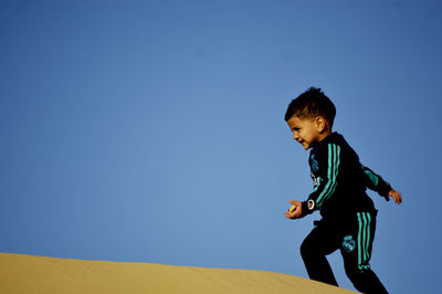 Low angle view of boy against clear sky