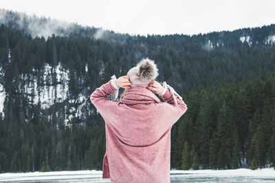 Woman standing on snow covered trees against mountain