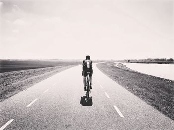 Rear view of man riding bicycle on road