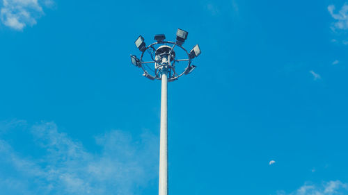 Low angle view of floodlights against blue sky