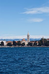 View of buildings at waterfront against blue sky