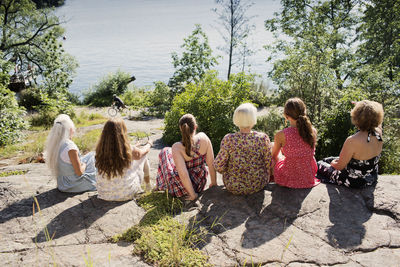 Rear view of women sitting on plants against trees