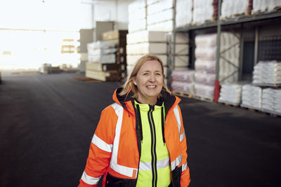 Portrait of smiling female blue-collar worker in distribution warehouse