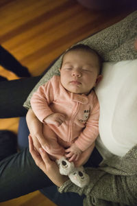 Newborn baby girl sleeps peacefully in mother's arms indoors