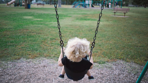 Rear view of girl swinging at playground