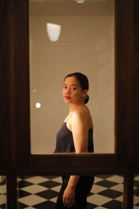 Young woman standing by glass on floor