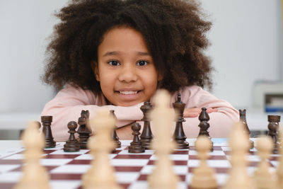 African american girl playing chess. happy smiling child behind chess in class or school lesson