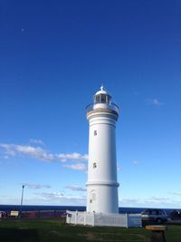 Low angle view of lighthouse by building against blue sky