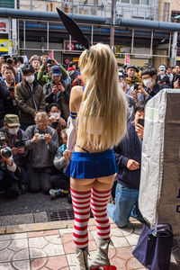 Rear view of people standing on street in city