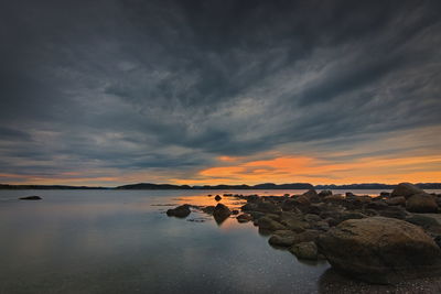 Rocks on sea against sky during sunset