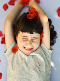 Close-up of cheerful girl with flowers lying on bed