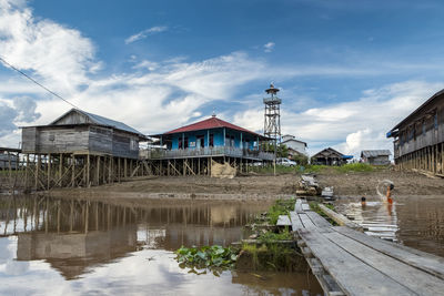 Buildings by lake against sky