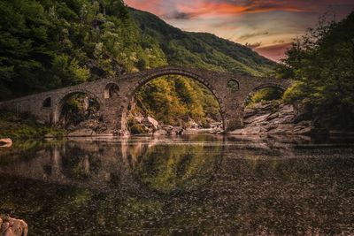 Arch bridge over river against sky