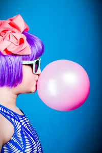 Portrait of woman with pink balloons against blue background