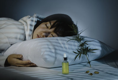 Asian girl sleeping in evening bedroom with cbd oil, capsules and a cannabis branch. melatonin 