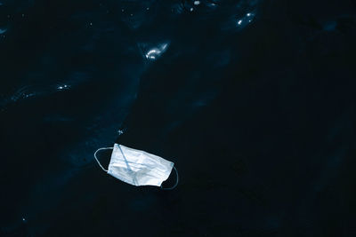 Disposable medical face mask floating in the open water. biohazard, covid ocean pollution