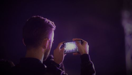 Rear view of man photographing through smart phone