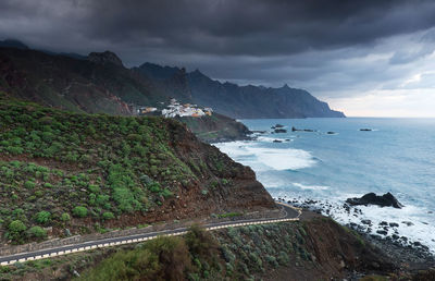 Scenic view of mountains by sea against cloudy sky