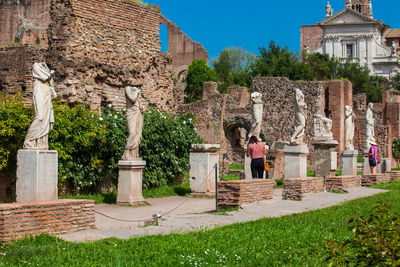 Tourists visiting the ancient ruins of the house of the vestal virgins at the roman forum in rome