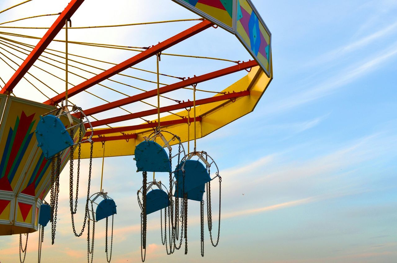 sky, low angle view, amusement park, ferris wheel, amusement park ride, arts culture and entertainment, cloud - sky, sunset, cloud, metal, multi colored, outdoors, built structure, no people, blue, part of, hanging, yellow, day, sunlight