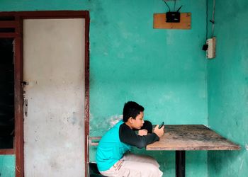 Young man sitting on wall