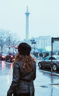 Rear view of woman standing in city during snowfall